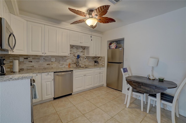 kitchen with sink, light tile patterned floors, appliances with stainless steel finishes, white cabinetry, and backsplash