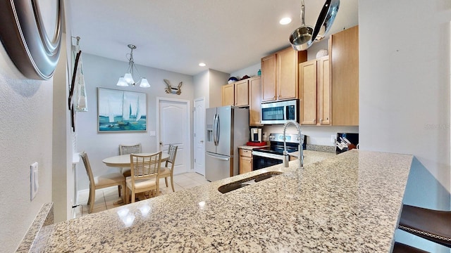 kitchen with appliances with stainless steel finishes, a breakfast bar area, hanging light fixtures, kitchen peninsula, and light brown cabinets