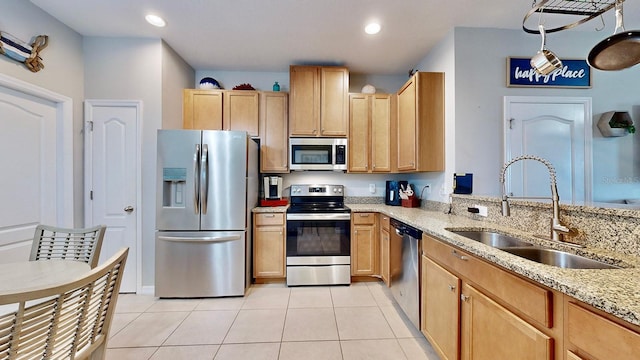 kitchen featuring appliances with stainless steel finishes, sink, light tile patterned floors, light stone countertops, and light brown cabinets