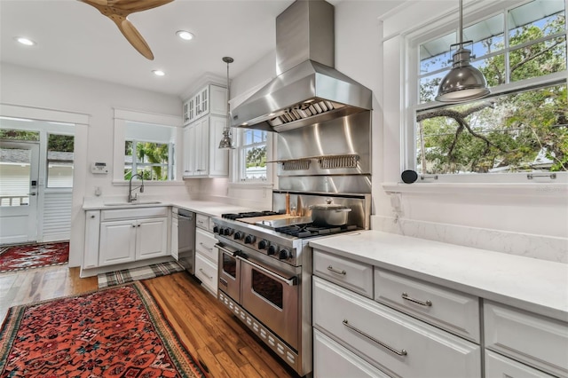 kitchen with sink, white cabinetry, decorative light fixtures, appliances with stainless steel finishes, and island exhaust hood