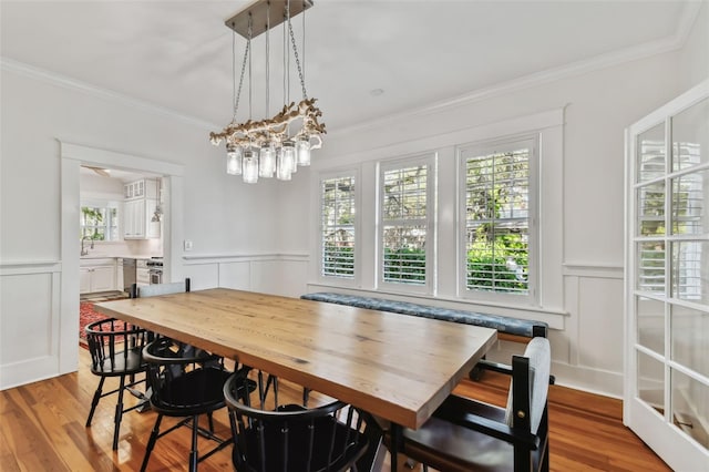 dining room featuring an inviting chandelier, ornamental molding, and light wood-type flooring