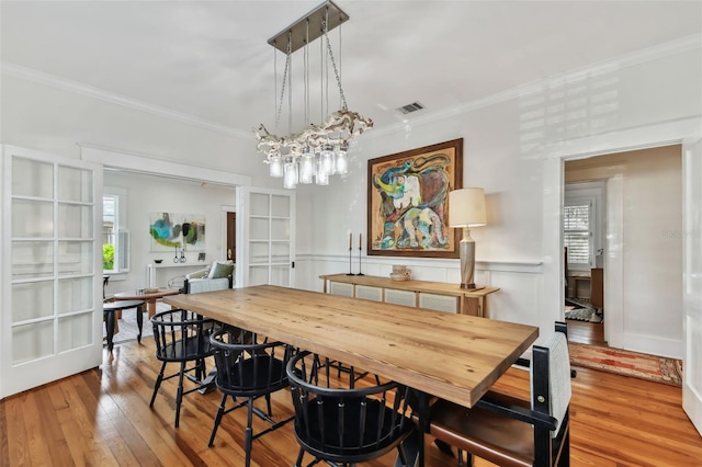 dining area with wood-type flooring and ornamental molding