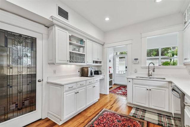 kitchen featuring stainless steel dishwasher, sink, light hardwood / wood-style flooring, and white cabinets