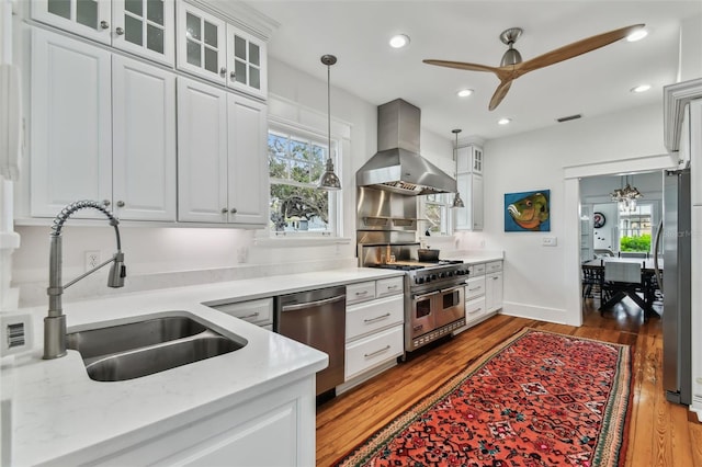 kitchen featuring pendant lighting, sink, appliances with stainless steel finishes, white cabinets, and exhaust hood