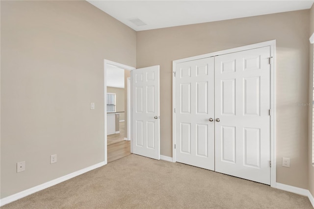 unfurnished bedroom with lofted ceiling, light colored carpet, and a closet