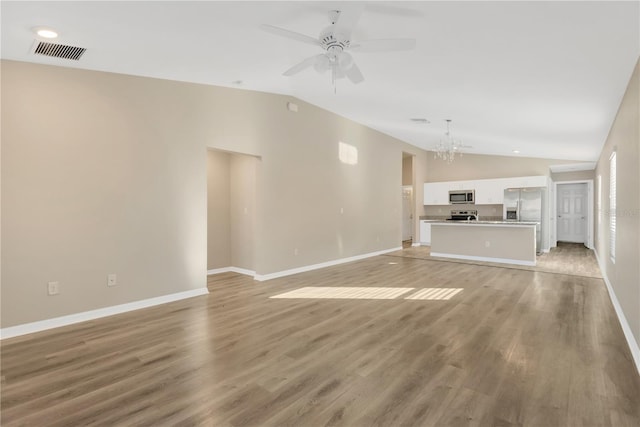 unfurnished living room featuring lofted ceiling, ceiling fan with notable chandelier, and light hardwood / wood-style flooring