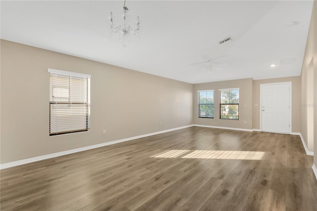 unfurnished room with dark wood-type flooring and ceiling fan with notable chandelier