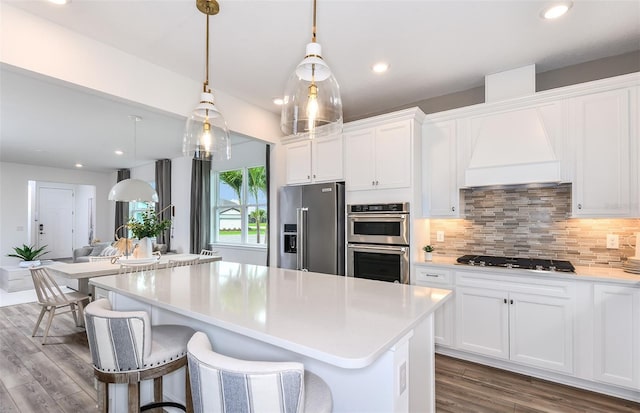 kitchen with stainless steel appliances, white cabinetry, hanging light fixtures, and a center island