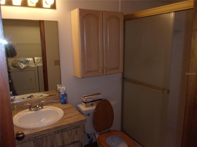 bathroom featuring vanity, washer and clothes dryer, a shower with shower door, and toilet