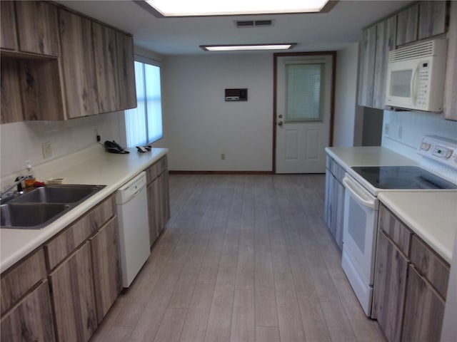 kitchen with sink, white appliances, light hardwood / wood-style floors, and backsplash