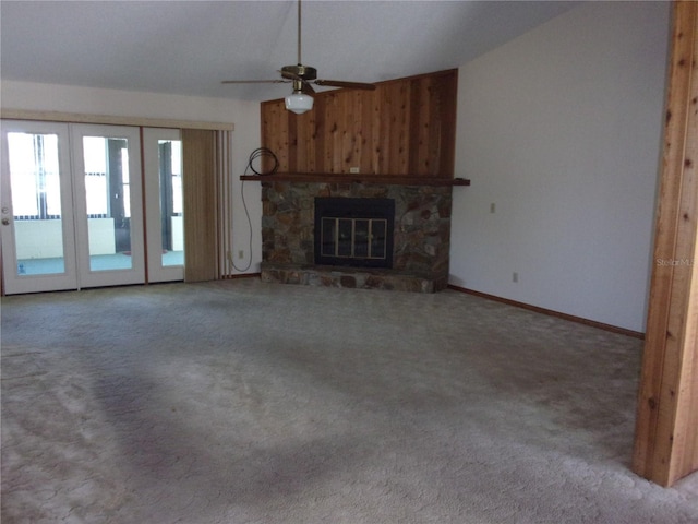 unfurnished living room with a fireplace, wood walls, lofted ceiling, carpet flooring, and ceiling fan