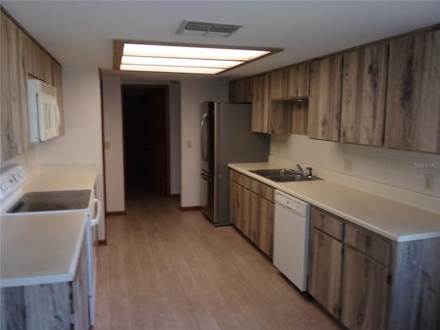 kitchen featuring sink, white appliances, and light wood-type flooring