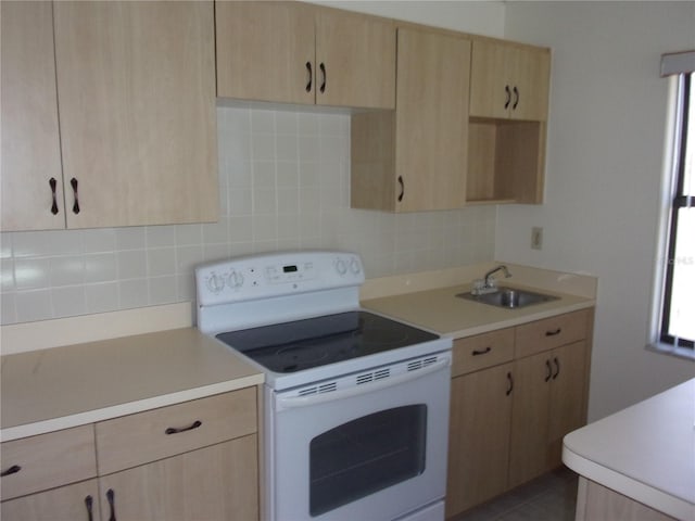 kitchen with white range with electric cooktop, light brown cabinetry, and sink