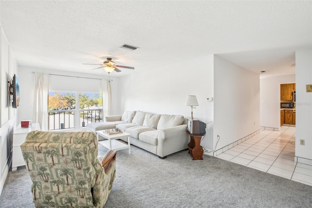 living room featuring ceiling fan, light colored carpet, and a textured ceiling