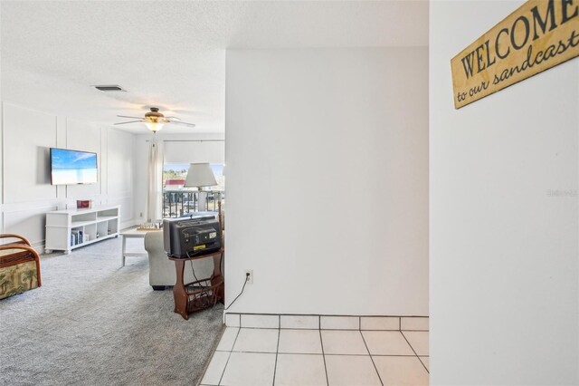 carpeted living room with a textured ceiling and ceiling fan