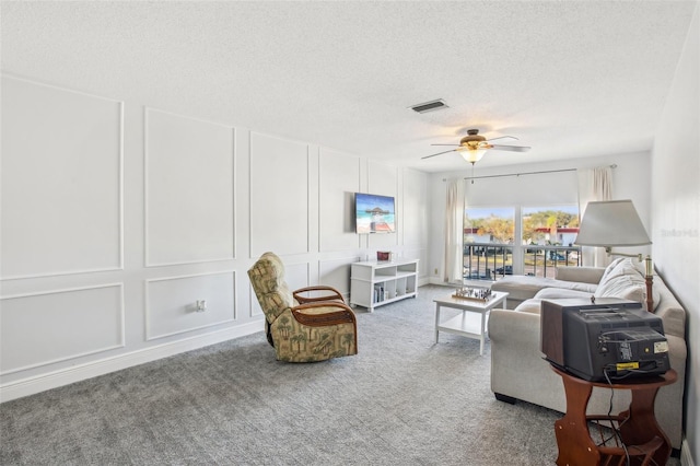 living room featuring ceiling fan, carpet floors, and a textured ceiling