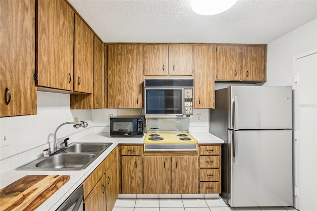 kitchen with light tile patterned flooring, sink, a textured ceiling, appliances with stainless steel finishes, and backsplash