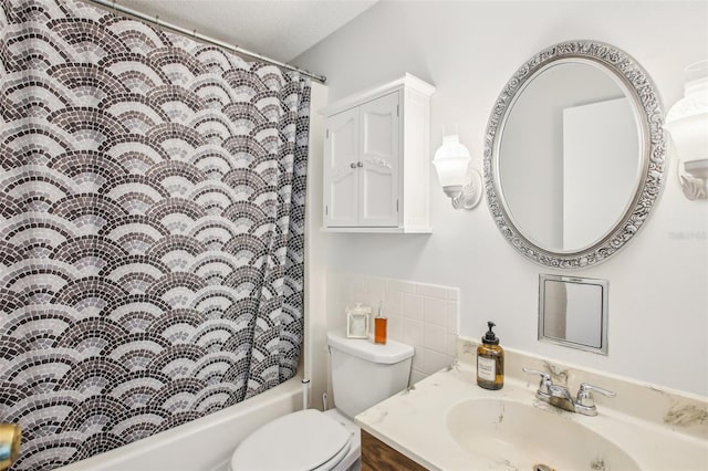 full bathroom featuring vanity, toilet, shower / bath combo with shower curtain, and a textured ceiling