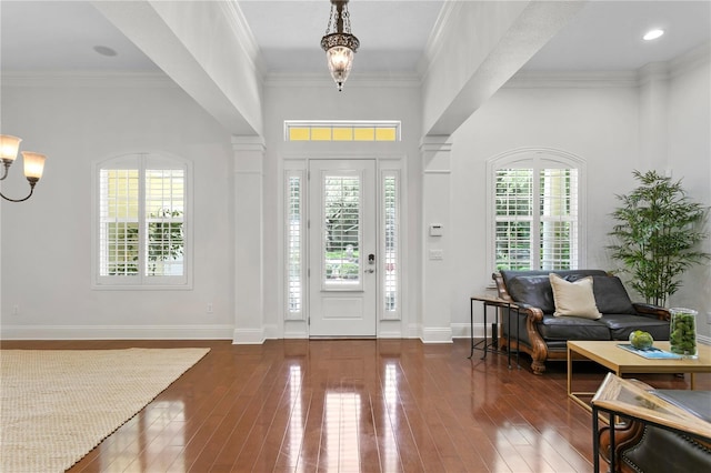 foyer entrance with crown molding, dark wood-type flooring, and a chandelier