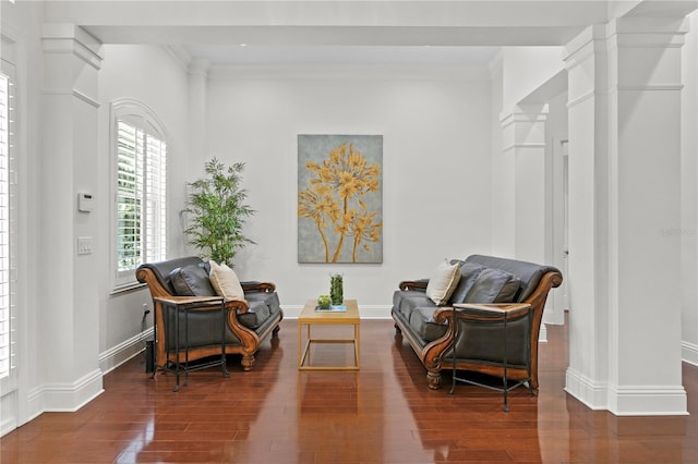 living area with ornate columns, crown molding, and dark hardwood / wood-style flooring