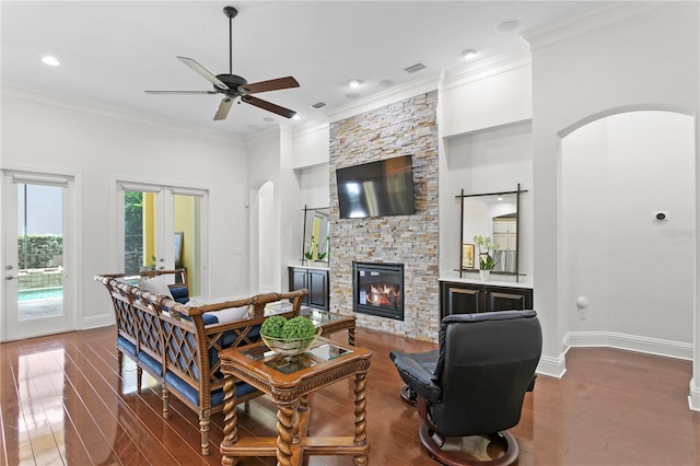 living room with wood-type flooring, a stone fireplace, crown molding, and french doors