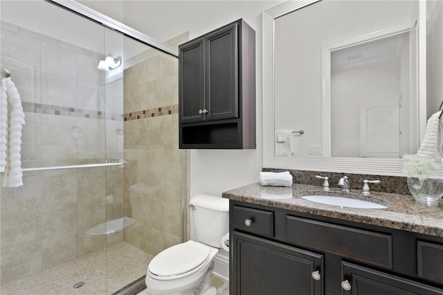 bathroom with toilet, vanity, and a shower with shower door