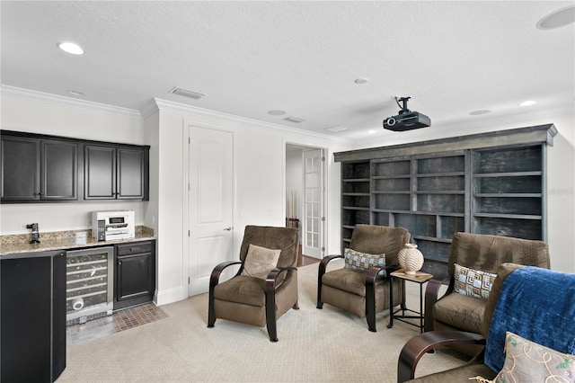 sitting room featuring crown molding, wine cooler, a textured ceiling, bar area, and light colored carpet