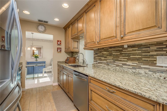 kitchen featuring tasteful backsplash, stainless steel appliances, light stone countertops, and sink