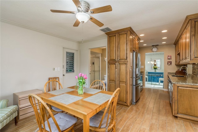 dining room featuring sink, crown molding, light hardwood / wood-style flooring, and ceiling fan