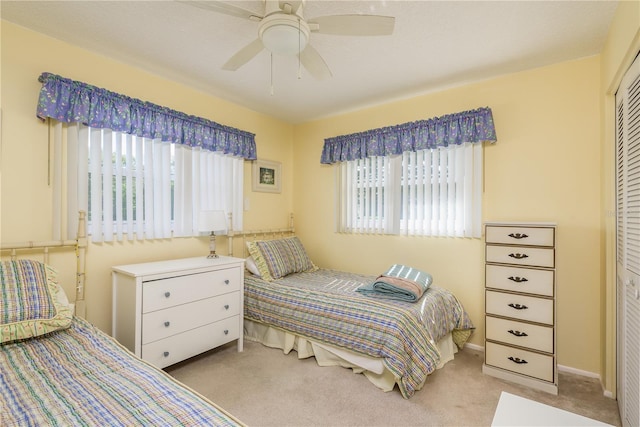 bedroom featuring multiple windows, light carpet, a closet, and ceiling fan