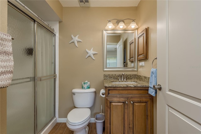 bathroom featuring vanity, toilet, and a shower with door