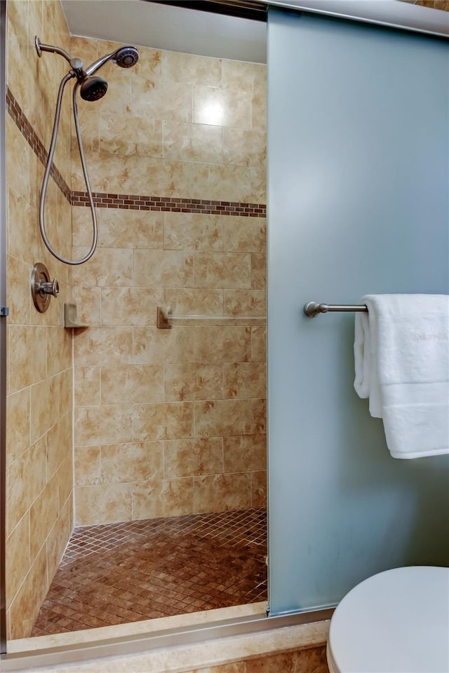 bathroom featuring a tile shower and toilet