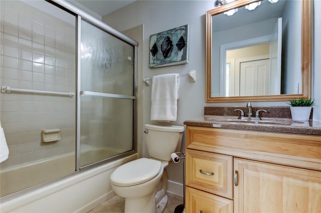 full bathroom with vanity, bath / shower combo with glass door, tile patterned floors, and toilet