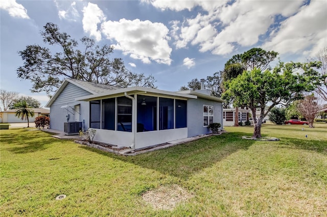 rear view of property with a yard, central AC unit, and a sunroom