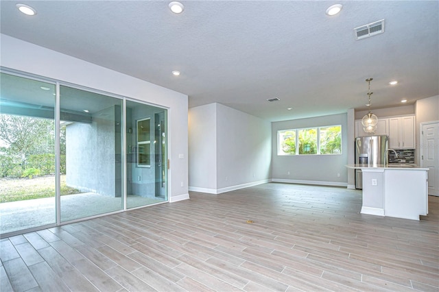 unfurnished living room featuring sink and light wood-type flooring