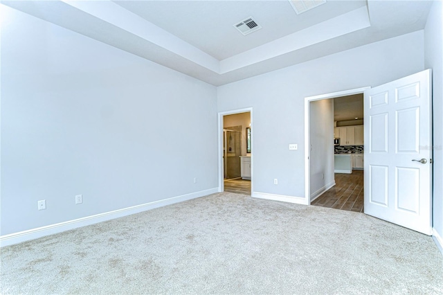 unfurnished bedroom with a tray ceiling and carpet