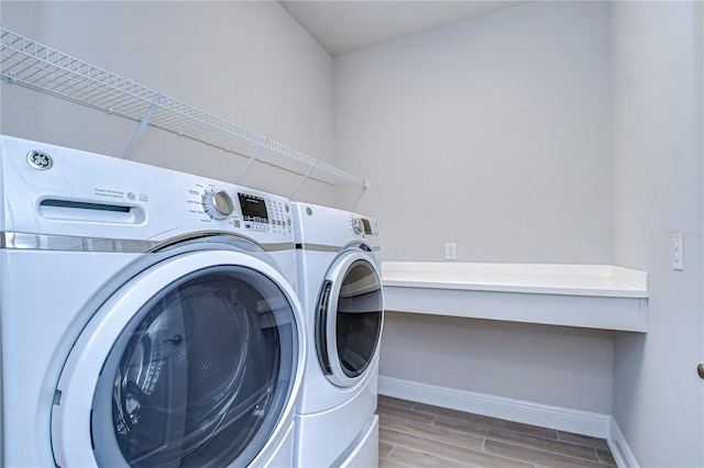 washroom with washing machine and dryer and light hardwood / wood-style flooring