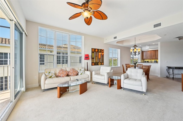 living room featuring light colored carpet and ceiling fan with notable chandelier