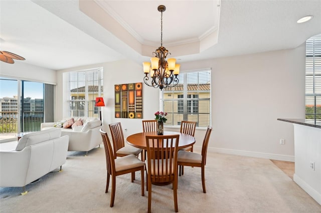 dining area featuring crown molding, a healthy amount of sunlight, a raised ceiling, and light carpet