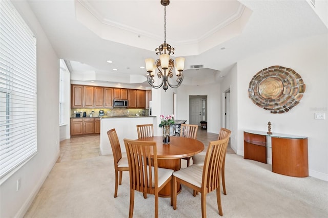 dining room featuring a chandelier, crown molding, a raised ceiling, and light carpet