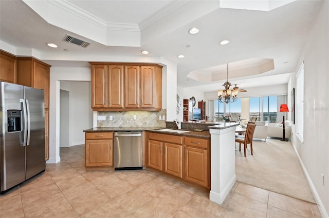 kitchen featuring a raised ceiling, backsplash, ornamental molding, kitchen peninsula, and stainless steel appliances