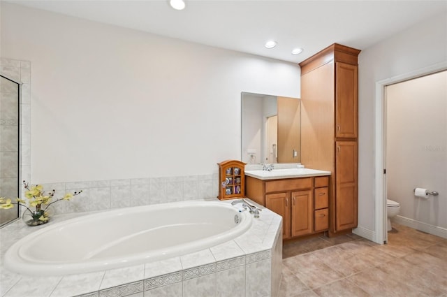 bathroom featuring vanity, toilet, tile patterned flooring, and tiled bath