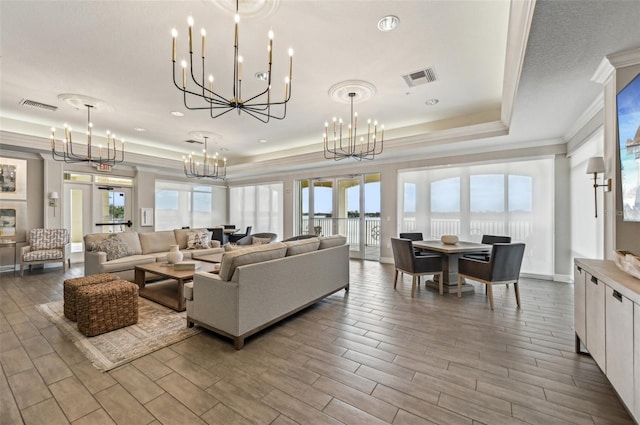 living room with an inviting chandelier, a tray ceiling, crown molding, and french doors