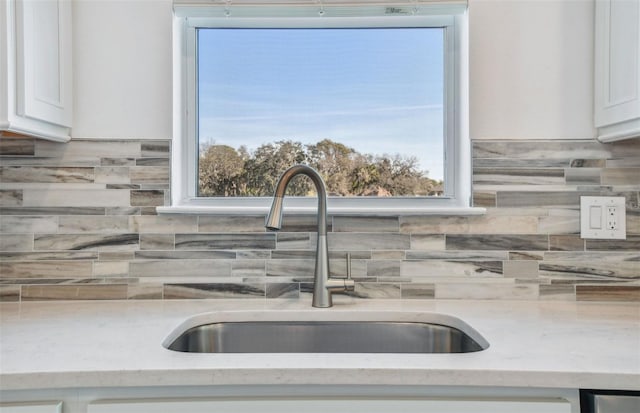 kitchen with plenty of natural light, light stone countertops, sink, and white cabinets