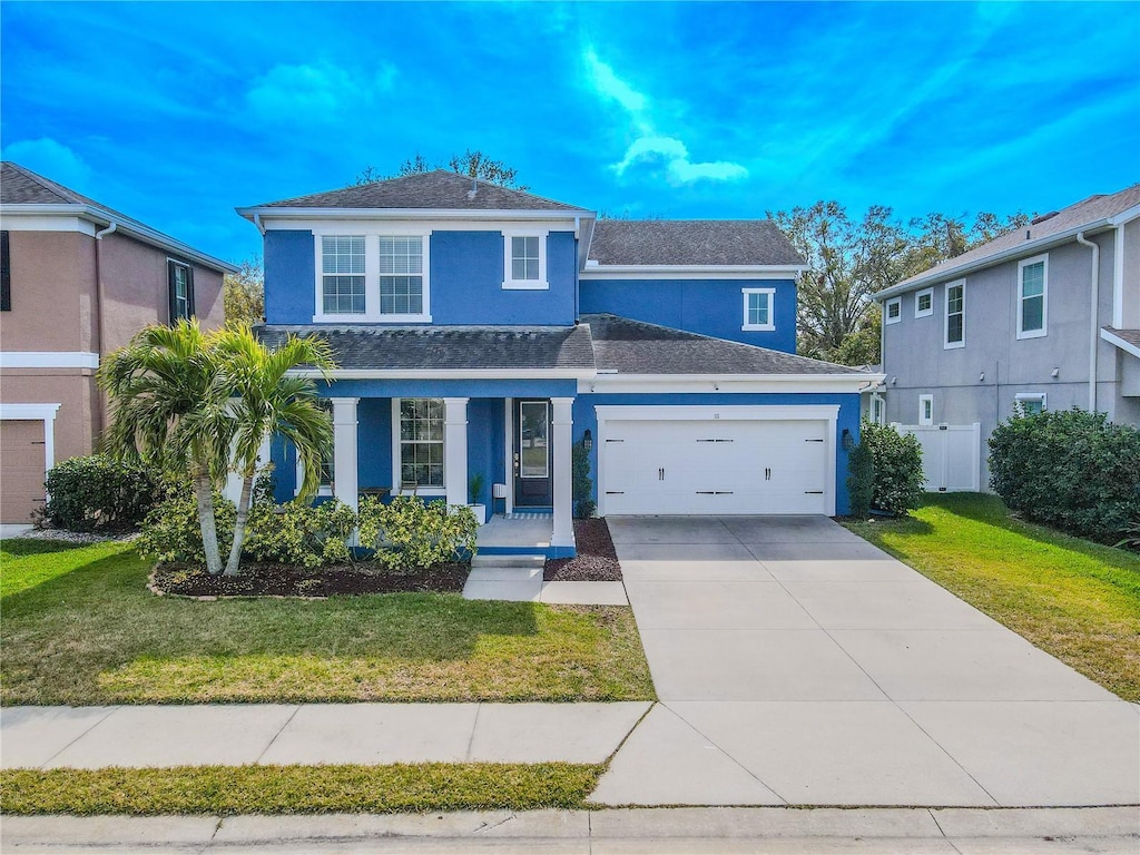 view of property with a garage, a front lawn, and a porch