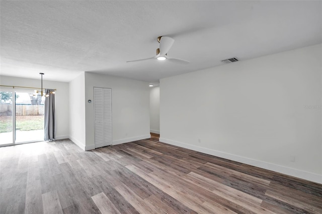 unfurnished room with ceiling fan with notable chandelier and hardwood / wood-style floors