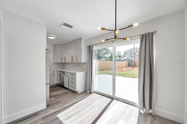 kitchen with dishwasher, an inviting chandelier, light hardwood / wood-style floors, and decorative backsplash