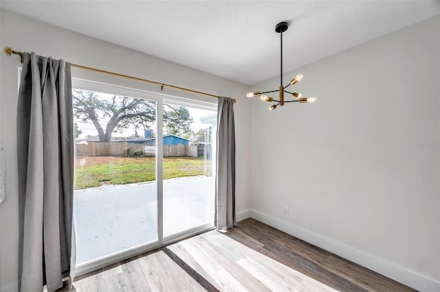 unfurnished dining area with hardwood / wood-style floors and a notable chandelier