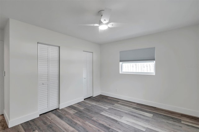 unfurnished bedroom featuring light wood-type flooring, two closets, and ceiling fan