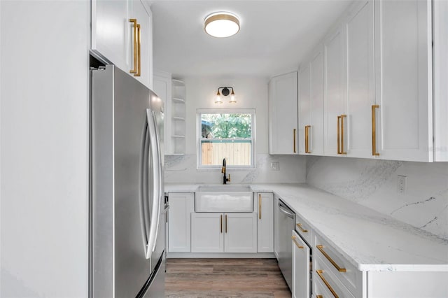 kitchen featuring appliances with stainless steel finishes, sink, white cabinets, decorative backsplash, and light stone countertops